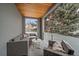 A covered patio features wicker furniture, patterned pillows, and a calming view of snow-covered evergreens at 1437 Garfield St, Denver, CO 80206