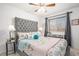 Inviting bedroom with tufted headboard, patterned bedding, and a ceiling fan offers comfort and style for a peaceful retreat at 15776 E 107Th Way, Commerce City, CO 80022