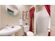 Well-lit bathroom featuring a white pedestal sink, toilet, framed art and a shower with a red curtain at 13307 Humboldt Dr, Thornton, CO 80241