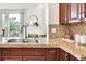 Close up of kitchen featuring granite countertops and cherry cabinets with sink overlooking the living room fireplace at 1862 Mallard Dr, Superior, CO 80027