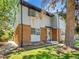 Charming two-story townhome with brick accents, gray siding, a black roof, and mature trees in a lush, green yard at 3061 W 92Nd Ave # 14A, Westminster, CO 80031