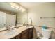 Well lit bathroom with a double sink vanity, decorative tile and a combination tub and shower with neutral colored shower curtain at 6132 W 113Th Ave, Westminster, CO 80020