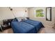 Bedroom featuring a queen-sized bed with a blue comforter, a side table, a window with green trees and carpeted floor at 6132 W 113Th Ave, Westminster, CO 80020