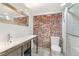 Modern bathroom featuring stylish vanity, exposed brick wall, and glass enclosed shower at 3306 N Gilpin St, Denver, CO 80205