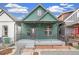 Green home featuring an inviting front porch with decorative ironwork and gray steps at 3306 N Gilpin St, Denver, CO 80205