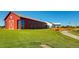 Expansive red barn on a lush green lawn with a curved walkway, perfect for events and storage at 10153 Pagosa St, Commerce City, CO 80022