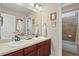 Bathroom with double sinks, wood cabinets, large mirrors, and a shower/tub combo at 10153 Pagosa St, Commerce City, CO 80022