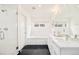 Bathroom featuring black slate floors, glass shower, soaking tub, and white marble double vanity at 3957 Utica St, Denver, CO 80212