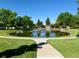 Scenic view of community pond surrounded by lush green trees and lawn at 53 Douglas S Dr, Broomfield, CO 80020