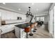 Open-concept kitchen featuring white cabinets, dark countertops, an island with seating, and a seamless flow to the dining area at 9406 Bross St, Arvada, CO 80007