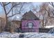 A view of the front of the two-story pink home with black fence and mature trees at 234 S Washington St, Denver, CO 80209