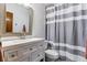 Bathroom with a vanity, framed mirror and tub with white and grey striped shower curtain at 5370 S Flanders Way, Centennial, CO 80015