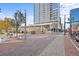 A street-level view of a modern building and public plaza with trees, seating, and a bicycle rack at 1750 Wewatta St # 1301, Denver, CO 80202