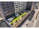 An aerial view of a serene outdoor rooftop lounge and garden area surrounded by modern buildings at 1750 Wewatta St # 1301, Denver, CO 80202