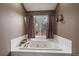 Jetted tub in bathroom with white tile and purple window treatments at 9251 Sand Hill Trl, Highlands Ranch, CO 80126