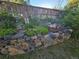 Charming stone-lined garden bed with patriotic decor and a variety of flowering plants against a wooden fence at 9251 Sand Hill Trl, Highlands Ranch, CO 80126