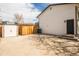 Exterior view of the home's backyard with a storage shed and wood fence features a concrete patio and home entrance at 441 Elbert Way, Denver, CO 80221