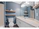 Bathroom featuring stylish blue walls, floating wood shelves, and white vanity with lots of counter space at 1473 Red Cliff Way, Castle Rock, CO 80109