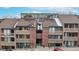 Three-story condominium complex featuring brick and wood facade and balconies on each level at 12368 W Nevada Pl # 303, Lakewood, CO 80228