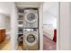 A laundry closet featuring a stacked washer and dryer, shelving, with view to bedroom at 12368 W Nevada Pl # 303, Lakewood, CO 80228