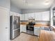 Cozy kitchen features white cabinets, stainless steel appliances, wood countertops, and tile flooring for an efficient cooking space at 298 S Hoover Ave, Louisville, CO 80027