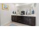 Bathroom with dual sinks, dark cabinets, a large mirror, and modern fixtures at 14278 Forest St, Thornton, CO 80602
