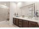 Bathroom featuring double sinks, dark wood cabinets, and a shower with tile surround at 14278 Forest St, Thornton, CO 80602