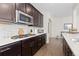 Close up on the kitchen with tile backsplash, gas cooktop, stainless steel microwave and dark wood cabinetry at 14278 Forest St, Thornton, CO 80602
