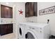 Modern laundry room with dark cabinets, washer, and dryer at 14278 Forest St, Thornton, CO 80602