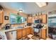 Sunlit kitchen with stainless steel appliances, wooden cabinets, and a tile floor at 4203 E 126Th Ave, Thornton, CO 80241