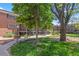 Exterior view of brick apartments with green lawn, mature trees, and walkways at 6800 E Tennessee Ave # 541, Denver, CO 80224