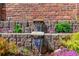 Close-up of a brick water feature with cascading water, colorful plants, and lush greenery at 11771 Elk Head Range Rd, Littleton, CO 80127