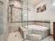 Modern bathroom featuring a glass-enclosed shower, soaking tub, and stylish tile work, offering a spa-like experience at 14855 Almstead St, Hudson, CO 80642