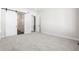 An empty bedroom with a sliding barn door and gray carpet at 6675 Fawn Path Ln, Castle Pines, CO 80108