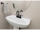 Stylish powder room featuring a modern pedestal sink and decorative mirror at 5129 Mt Arapaho Cir, Frederick, CO 80504