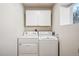 Functional laundry room with white washer and dryer, cabinets and natural light from window at 1430 Fairfax St, Denver, CO 80220