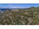 Aerial view of a house nestled amongst green trees and mountains with snow-capped peaks in the distance at 3945 Douglas Mountain Dr, Golden, CO 80403