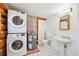 Bathroom features a stacked washer/dryer unit, toilet, pedestal sink, and tile flooring, combining functionality with rustic charm at 3945 Douglas Mountain Dr, Golden, CO 80403