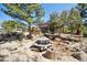 Log cabin features a picnic table, fire pit, mature trees, and rock outcroppings, creating a serene outdoor space at 3945 Douglas Mountain Dr, Golden, CO 80403