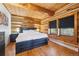 Inviting bedroom with log walls, wooden floors, a comfortable bed, and bright natural light at 3945 Douglas Mountain Dr, Golden, CO 80403