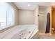Relaxing bathroom featuring a soaking tub with shower and a window for natural light at 46122 County Road 53, Bennett, CO 80102