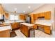 A well-lit kitchen featuring wood cabinets, tile floors and countertops and stainless steel appliances at 46122 County Road 53, Bennett, CO 80102