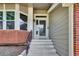 Inviting front entrance with a storm door, brick accents, and well-maintained landscaping at 3973 S Joplin Way, Aurora, CO 80013