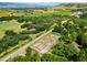 This aerial image presents a home's surroundings, showing the tennis court and serene countryside at 922 W Wolfensberger Rd, Castle Rock, CO 80109