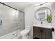 Modern bathroom features a glass shower, dark wooden vanity and a sleek round mirror at 922 W Wolfensberger Rd, Castle Rock, CO 80109