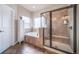 Bright bathroom featuring a soaking tub, glass-enclosed shower, and neutral tile at 253 E 8Th Ave, Byers, CO 80103