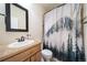 Bathroom with a wood vanity, decorative mirror, and shower with mountain-themed curtain at 253 E 8Th Ave, Byers, CO 80103