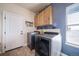 Modern laundry room featuring a front-load washer and dryer with overhead storage at 253 E 8Th Ave, Byers, CO 80103