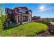 Spacious backyard featuring green lawn and landscaping surrounding a charming two-story red home at 4825 Basalt Ridge Cir, Castle Rock, CO 80108