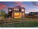 Charming two-story red home with a well-maintained backyard, wooden fence, and vibrant flowers at dusk at 4825 Basalt Ridge Cir, Castle Rock, CO 80108